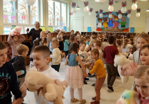Dzieci bawią się i tańczą podczas balu wraz ze swoimi pluszakami.