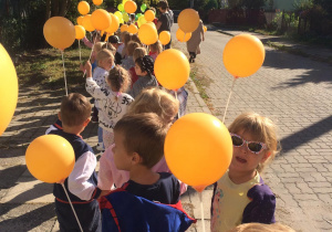 Dzieci z balonami na spacerze w pobliżu przedszkola.