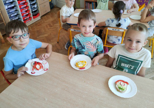 Dzieci ozdabiają kanapki kolorowymi warzywamiym.