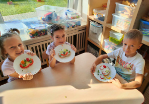 Dzieci ozdabiają kanapki kolorowymi warzywamiym.