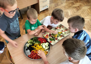 chłopcy układają warzywa na foccaci