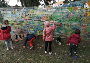 Dzieci malują farbami na folii.