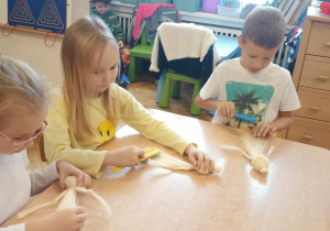Dzieci wykonują kolejne etapy pracy tworzenia aniołka ze sznurka.