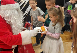 Dzieci częstują Mikołaja słodkościami.