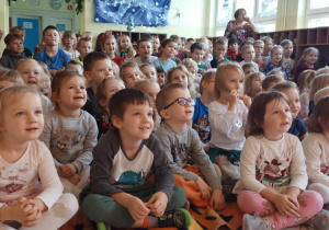 Dzieci zgromadzone w dolnym holu oglądają przedstawienie lalkowe