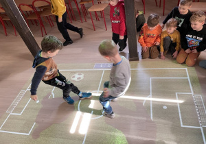 Dzieci grają w piłkę nożną na magicznym dywanie.