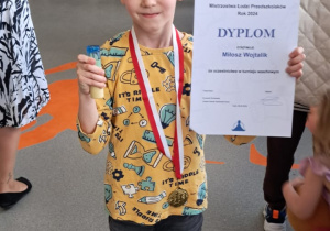 Chłopiec prezentuje zdobyty medal i dyplom