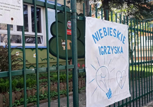 Baner z napisem Niebieskie Igrzyska na ogrodzeniu przedszkola