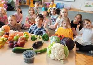 Dzieci pozują przy straganie z owocami i warzywami