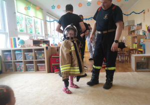 Dziecko przymierza strój strażaka.