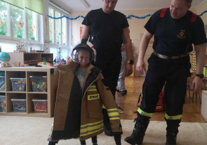 Dziecko przymierza strój strażaka.