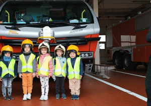 Dzieci pozują do zdjęcia z wozem strażackim.